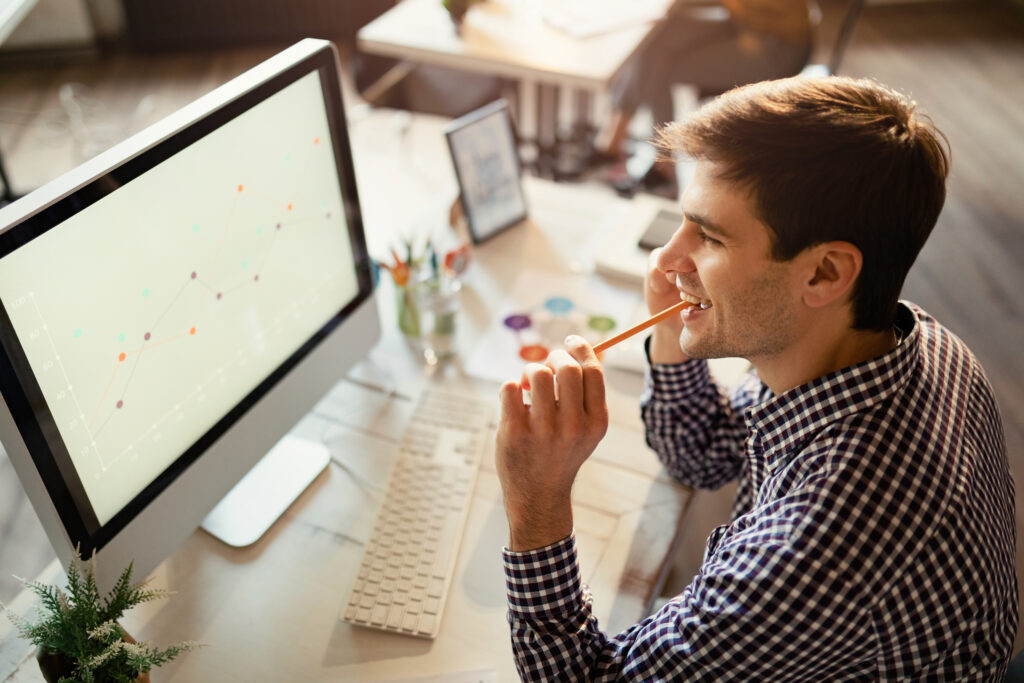 high-angle-view-smiling-entrepreneur-analyzing-business-progress-while-using-computer-office
